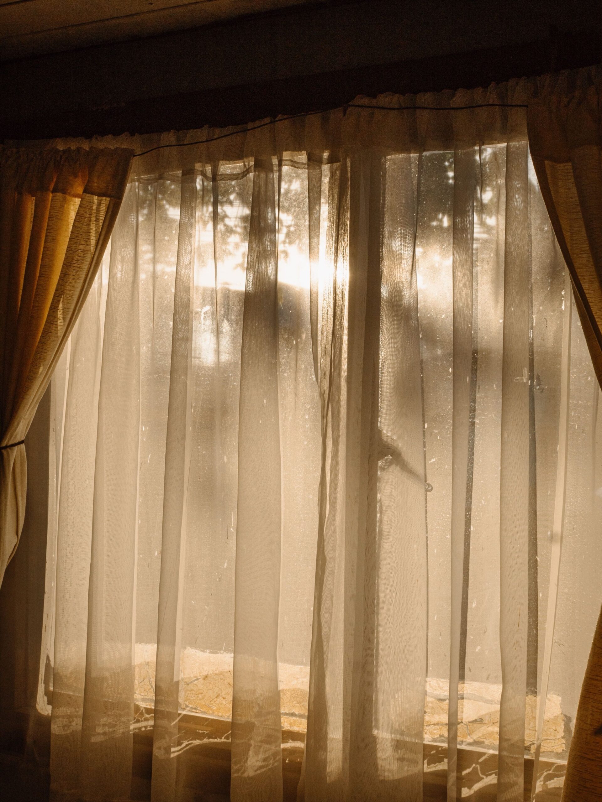 Morning sunlight streaming through sheer bedroom curtains during a healthy morning routine.